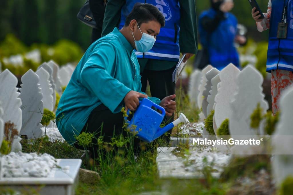    Abdul Rashid Zainal Arifin waters the grave of his mother at the Raudhatul Sakinah Muslim Cemetery in Selangor, while the representatives from MAIWP brought him there.     PIX: MUHD NA’IM / MalaysiaGazette / 15 APRIL 2022.