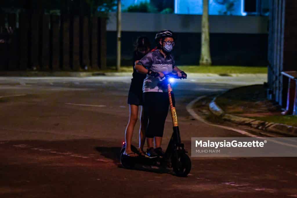 A mother riding an e-scooter with her daughter in the middle of the road, endangering the safety of her family and other motorists at Taman Tasik Perdana, Cyberjaya. PIX: MUHD NA’IM / MalaysiaGazette / 17 APRIL 2022