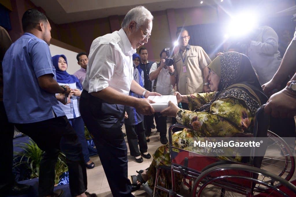    Datuk Seri Najib Tun Razak hands the Bantuan Rakyat 1 Malaysia (BR1M) to one of the disabled recipients during the national launch of Bantuan Rakyat 1 Malaysia (BR1M 2018) cash aid at the Sultan Haji Ahmad Shah Convention Hall in Pekan, Pahang.     PIX: FAREEZ FADZIL / MalaysiaGazette / 25 FEBRUARY 2018.