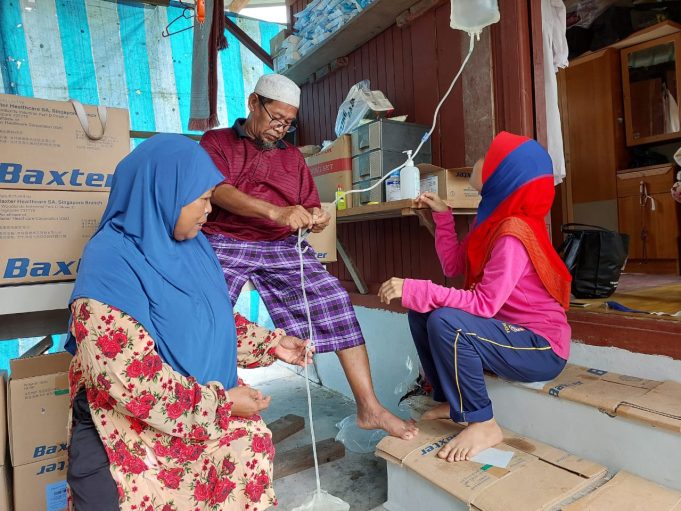 Hasan (tengah) terpaksa melakukan sendiri rawatan dialisis di rumah dalam dusun buah yang didiaminya secara percuma atas ihsan kenalan kerana tidak mampu untuk mendapatkan rawatan berkenaan di hospital.