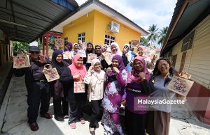 Tenaga Pengajar, Nuraini A Jalil (tengah) bergambar kenangan dengan para peserta sambil menunjukkan hasil karya seni beg jut di Pusat Komuniti Desa Gagu, Kuala Klawang, Jelebu. Foto FAREEZ FADZIL, 24 JULAI 2026.