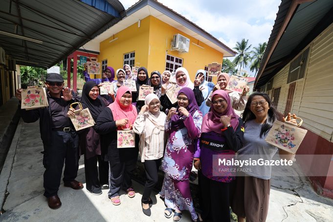 Tenaga Pengajar, Nuraini A Jalil (tengah) bergambar kenangan dengan para peserta sambil menunjukkan hasil karya seni beg jut di Pusat Komuniti Desa Gagu, Kuala Klawang, Jelebu. Foto FAREEZ FADZIL, 24 JULAI 2026.